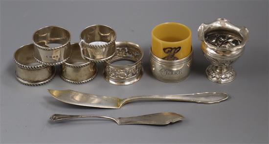 Seven assorted napkin rings including five silver and one French white metal, a small white metal vase and two butter knives.